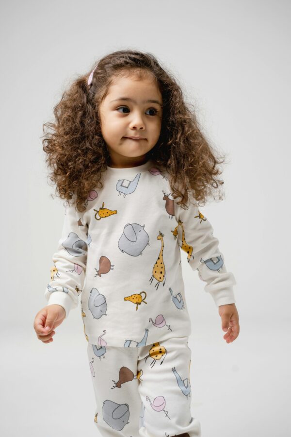 Cute little girl in animal print pajamas posing in a studio setting.