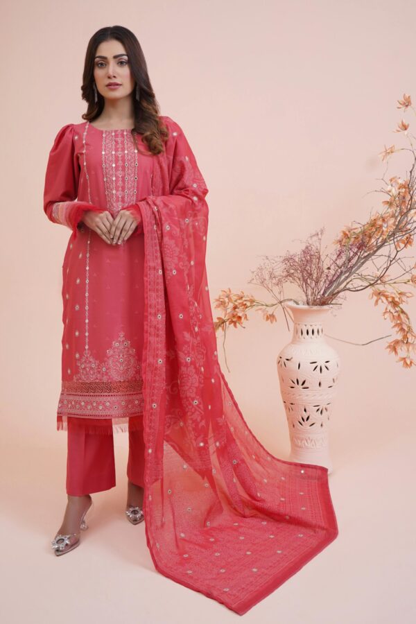 Model in traditional red Pakistani attire posing indoors with floral decor.